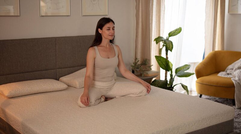 Kobieta medytuje na swoim wygodnym materacu na łóżku w sypialni